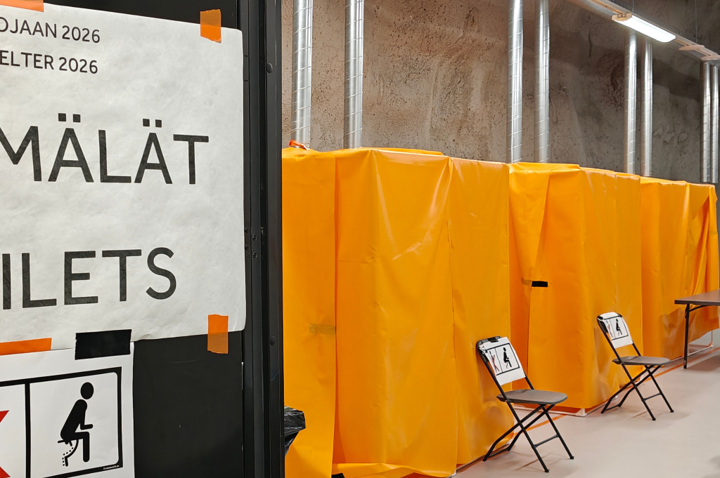 Käymälät-toilets-kyltti ja suojakankaat kuvassa.